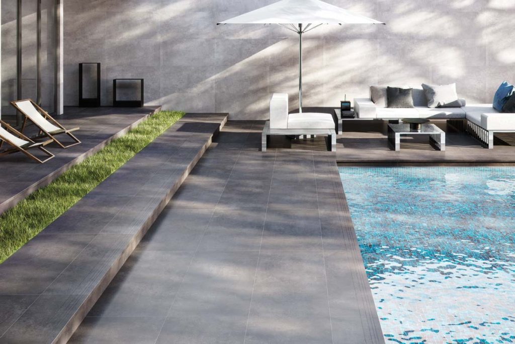 Outdoor dark grey stone effect tiles near swimming pool.